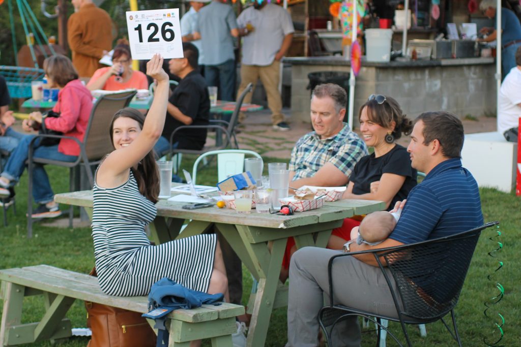 woman holds up auction sign at picnic table