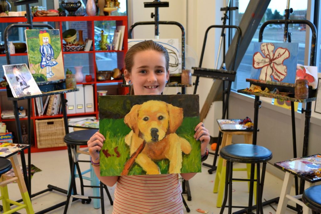 Young girl holds a painting of a puppy