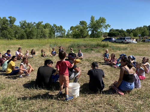 A group of people sit in a circle in a field