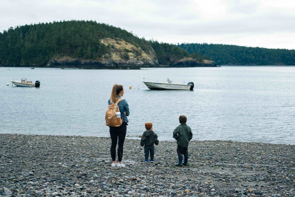 family with two young children stands near the water