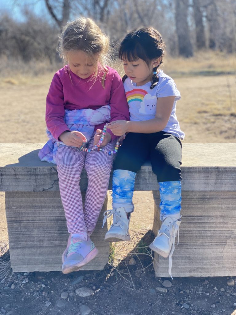 two young girls sitting outside on a bench