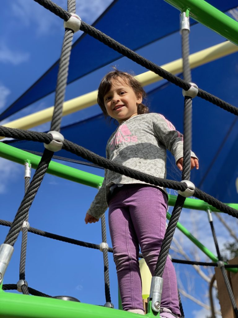 child smiles down from playground bridge