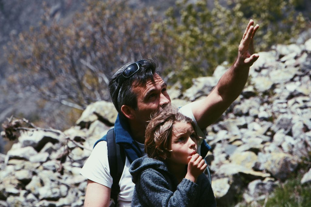 young boy and father looking up while on a hike